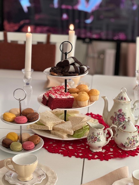 Ett dukat bord med kakfat i våningar med godsaker på, och en te-servis med blommönster och tända ljus